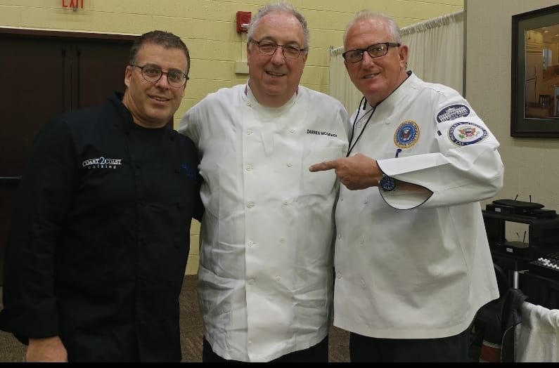 Three chefs posing together smiling